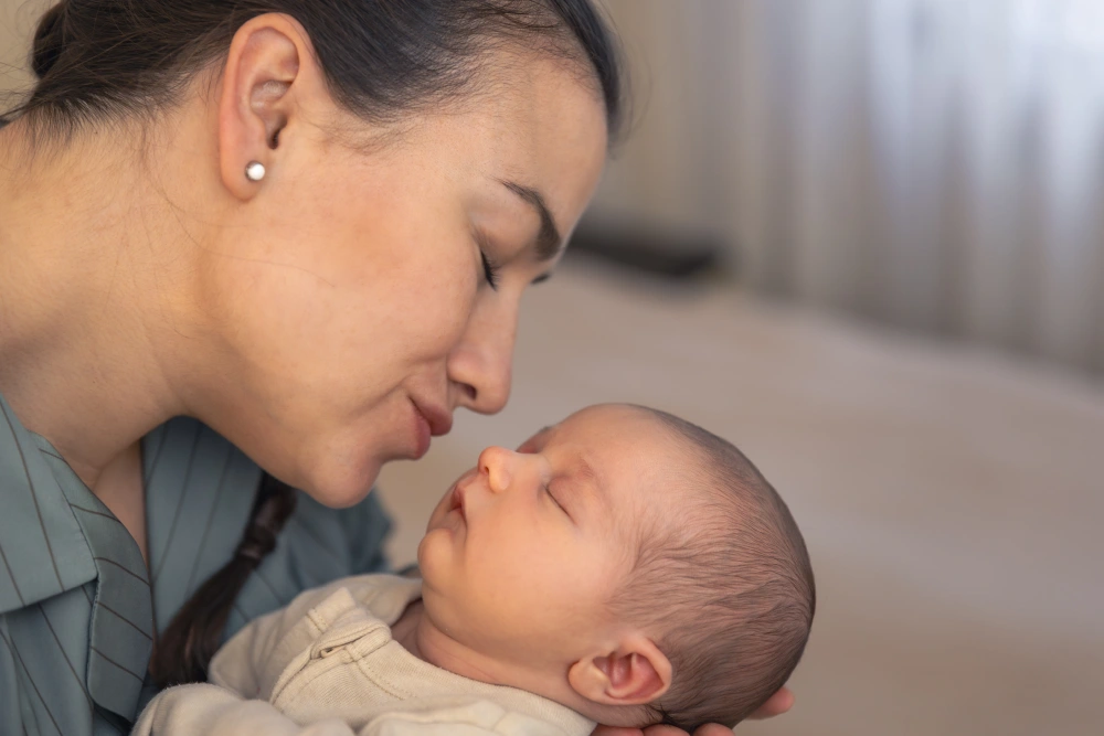 Mother kissing baby daughter newborn baby.